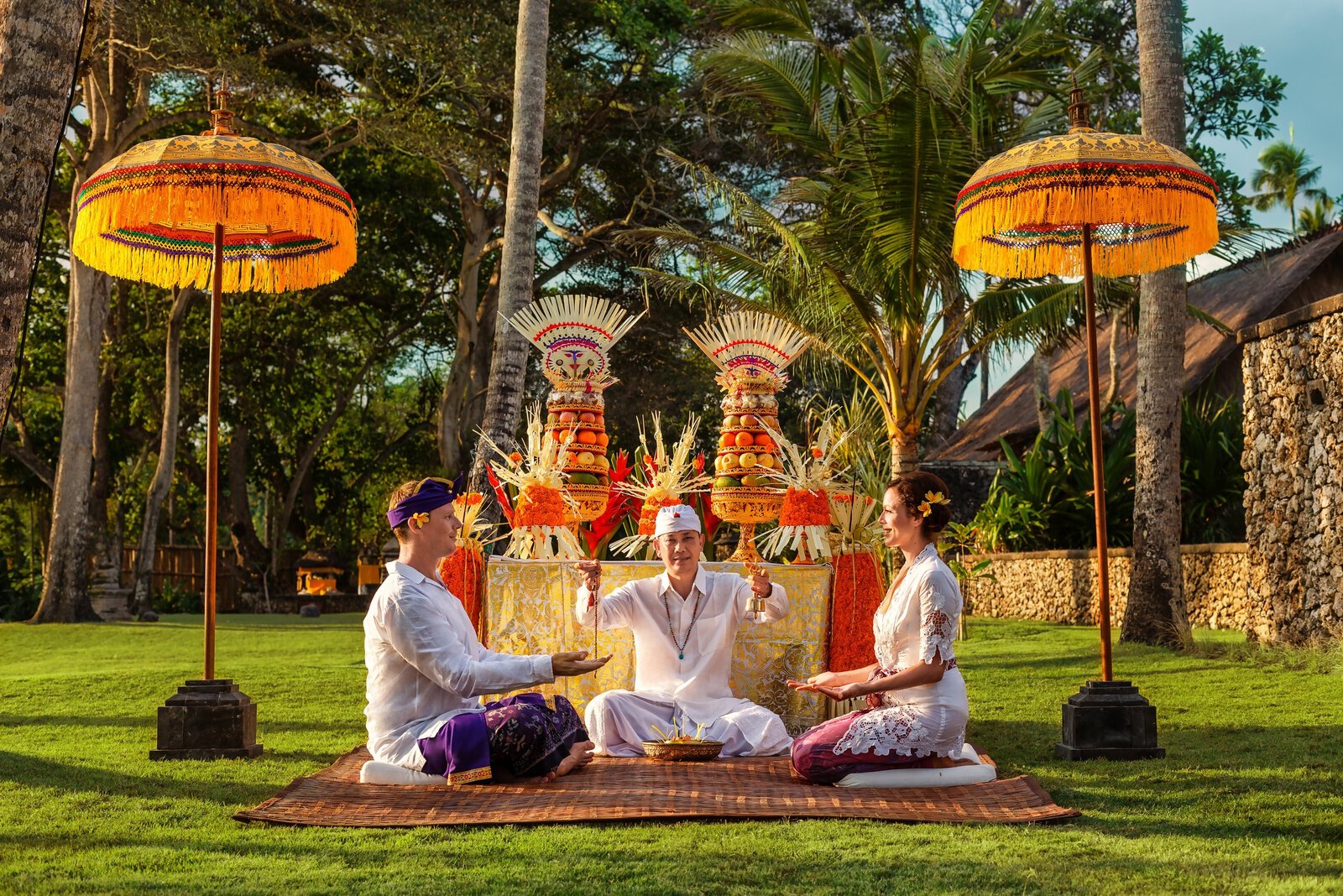 Couple at a Balinese vow renewal ceremony under ceremonial umbrellas