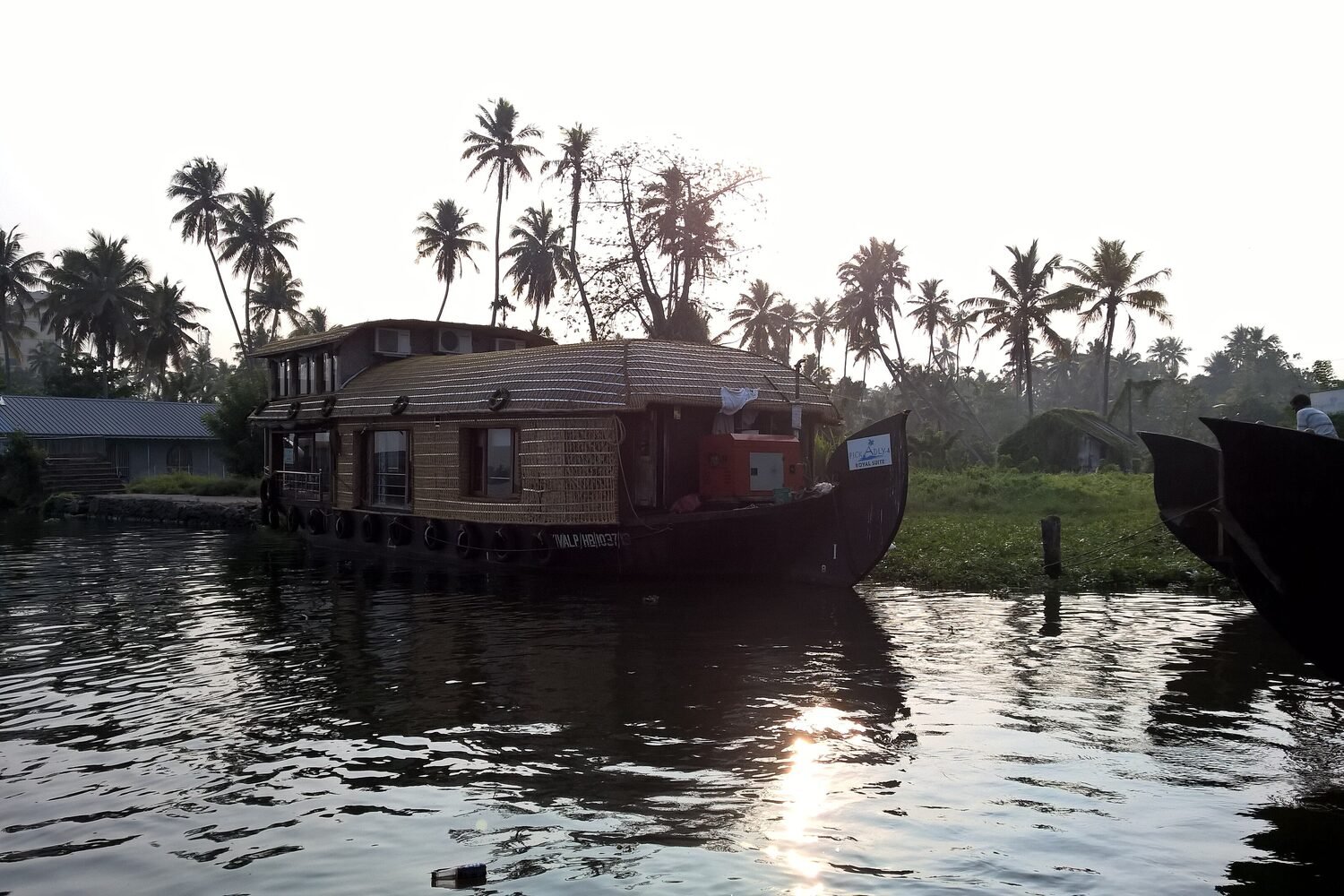 A Kerala houseboat moored among palms at sunset on the Alleppey backwaters
