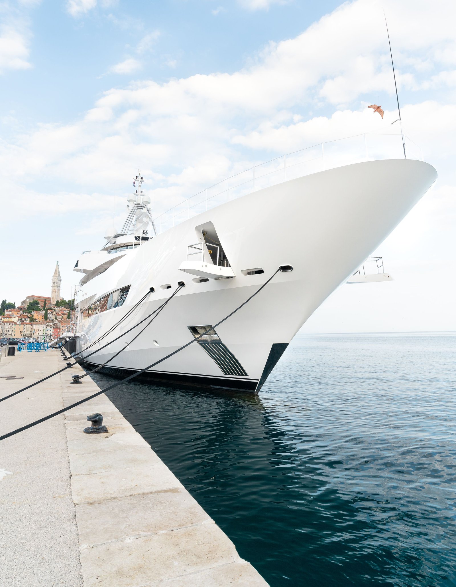 A luxury superyacht moored beside a historic Mediterranean coastal town