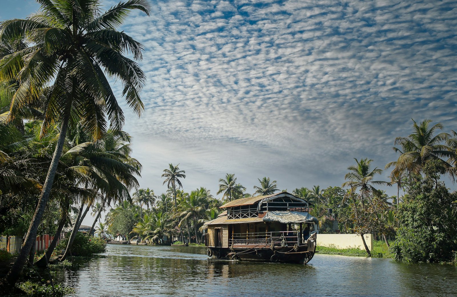 A traditional Kerala houseboat drifting through palm-lined backwaters